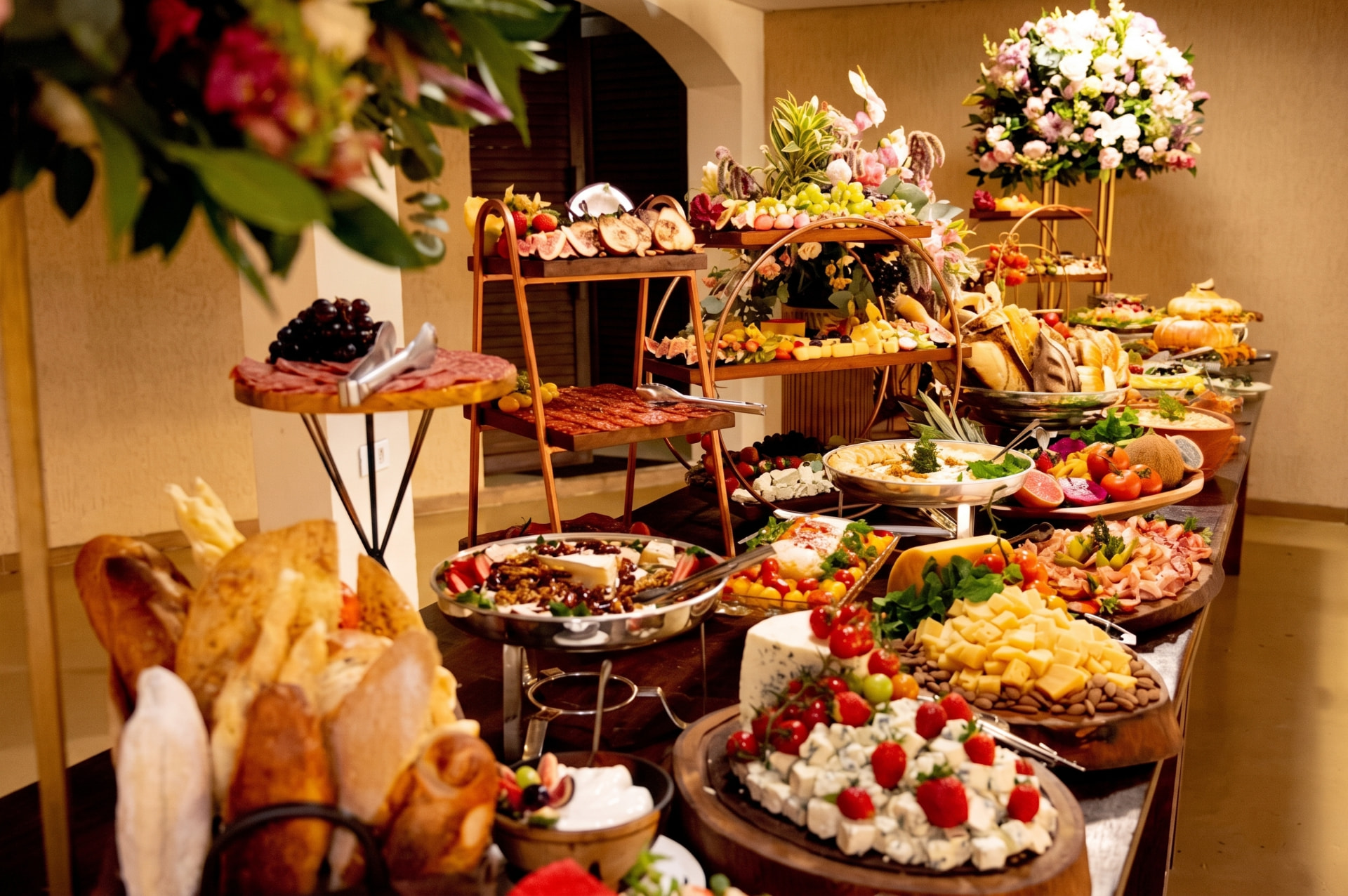 Ilha gastronômica do Infinity Gastronomia com queijos, frios, pães artesanais, frutas e flores